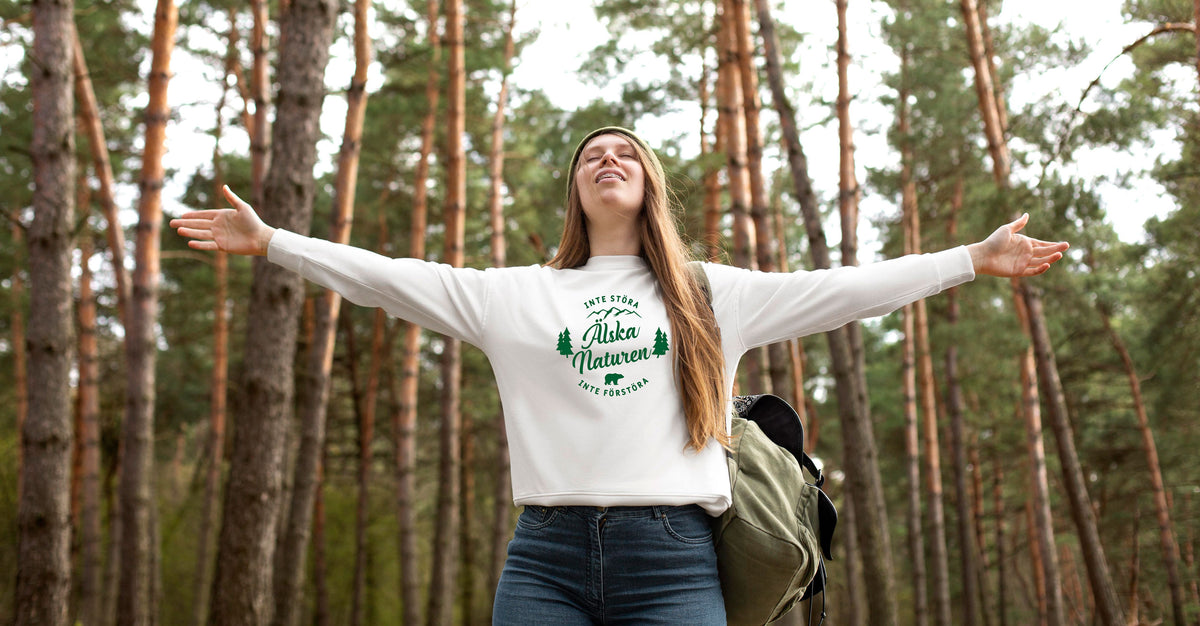 Kvinna iklädd vit tröja med texten "älska naturen" tryckt på i mörkgrön färg